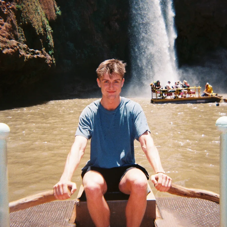 Pawel rowing a boat beside a waterfall